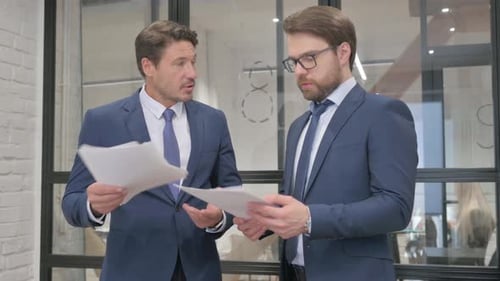 Business People Discussing Business Report while Standing in Office