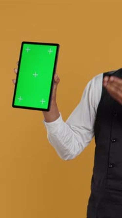Vertical Video Restaurant Waiter Presenting a Green Screen Layout on Tablet