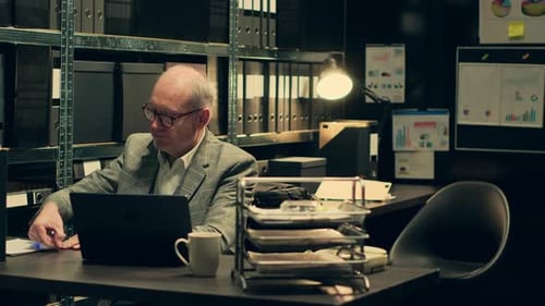 Mature Man Works on Laptop in Organized Office