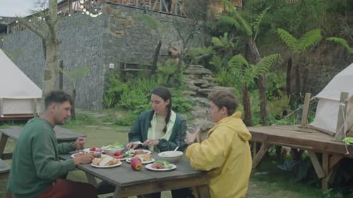 Friends Enjoying Picnic Lunch While Camping Outdoors