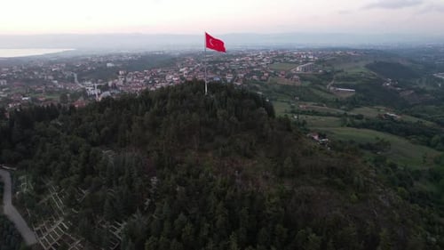 Flag Waves Atop Hill Near City