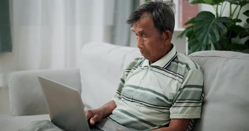 Senior Man Using Laptop on Couch at Home