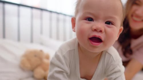 Infant Plays on Bed with Smiling Woman