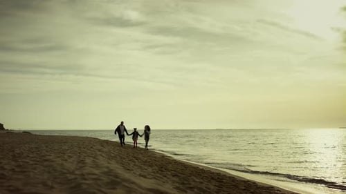 Glückliche Familie, die sich beim Sonnenaufgangsurlaub am Sandstrand zusammenfindet
