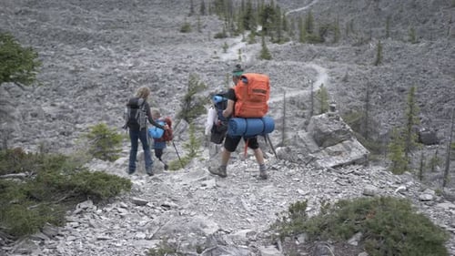 Friends Hing with Camping Backpacks on Rugged Rocky Mountain Trail Adult