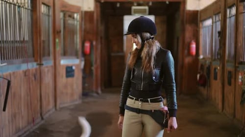 Dolly Shot Portrait of Smiling Woman in Helmet Walking in Stable Looking Around Front View Medium