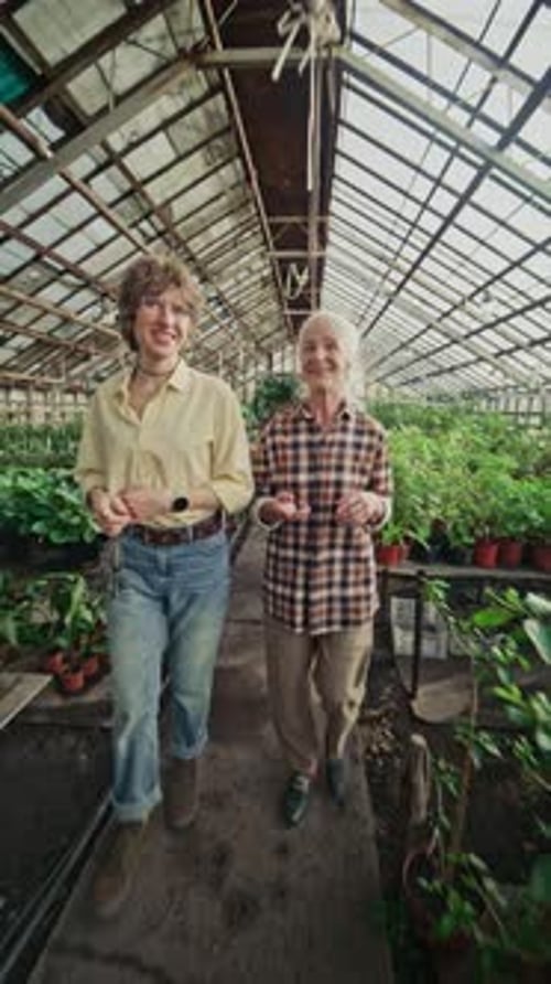 Two Women Walking in a Greenhouse Full of Plants