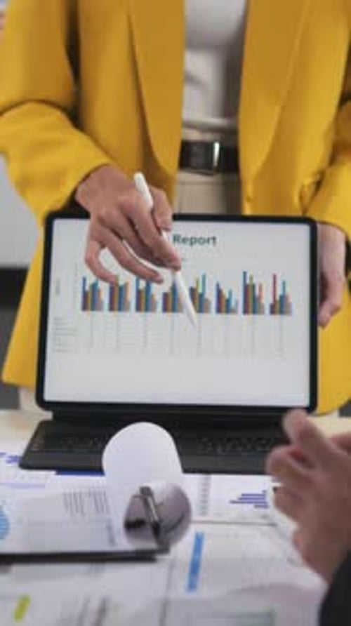 Business professionals analyze a sales report on a digital tablet during a meeting