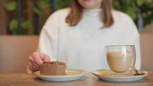 Woman Cuts Chocolate Dessert Beside Latte on Cafe Table