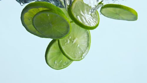 Lime Slices Falling into Water with Bubbles