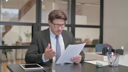 Middle Aged Businessman Feeling Upset while Reading Contract in Office