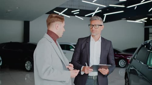 Professional Men Discussing Car in Modern Dealership