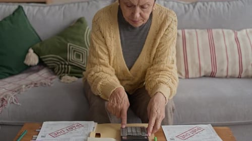 Senior Woman Stressed by Bills and Calculator at Home