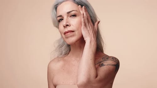 Senior Woman Examining Skin Health in Studio Shot