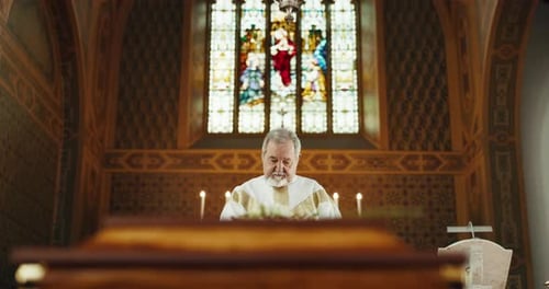 Funeral, church and priest praying by coffin for memorial service, sermon and ceremony for death