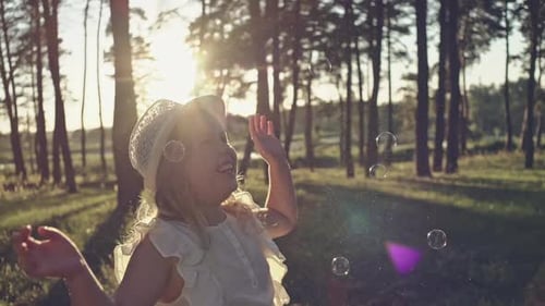Funny Little Girl Catching Soap Bubbles in the Summer on Nature