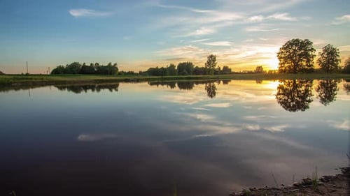 Golden sunset turns to magenta as the sky and colors reflect off the glassy surface of a lake - time