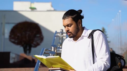 Happy Indian Male Student Reads Books Near the University