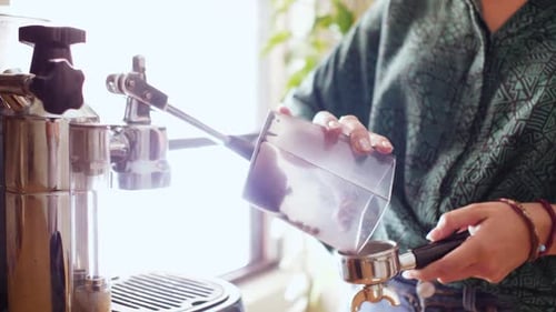 Frau gießt Kaffeemühle ein und bereitet frischen Kaffee zu