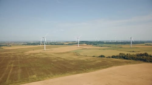 Wide aerial view of wind farm and agricultural fields. Farms on open plains dotted with wind power g
