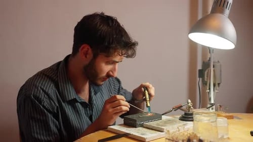 Der Handwerker arbeitet unter warmem Licht in einer Werkstattumgebung an detailliertem Design