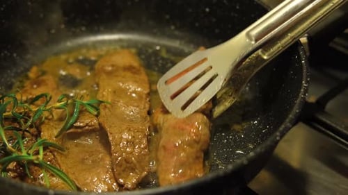 Close Up of Steak Frying in Pan with Rosemary