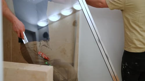 Workers Remove a Glass Shower Door Bathroom Renovation Construction Process Dismantling Shower
