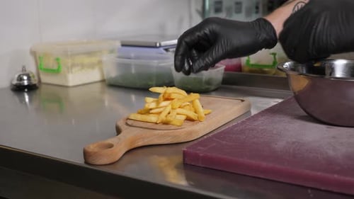 Person Placing Golden French Fries on Cutting Board