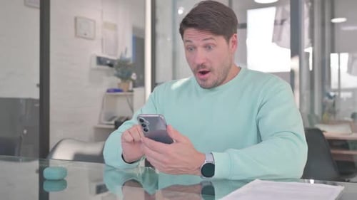Man Surprised and Excited by Message on Smartphone