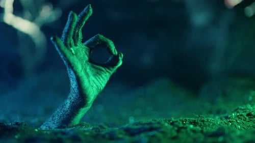 Zombie Arm Emerging Showing OK Sign at Night