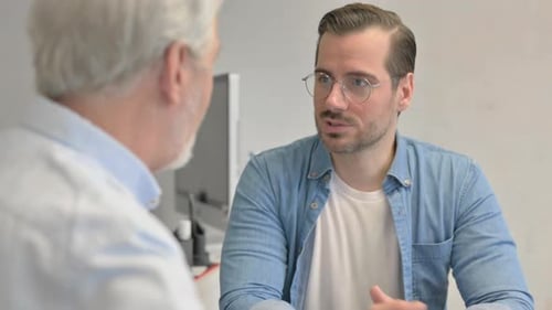 Close up of Young Man Talking with Teammate in Office