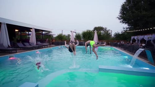Happy Friends Jumping and Splashing in Swimming Pool in Luxury Resort Young Men in Swimwear Having