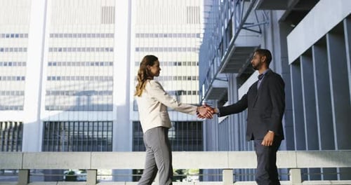 4k video footage of a young businessman and businesswoman shaking hands in the city