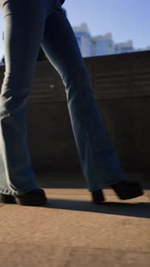 Female Legs in Jeans and Black Shoes Walk in the Sunset Light