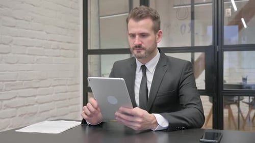Man Using Tablet at Desk in Modern Office