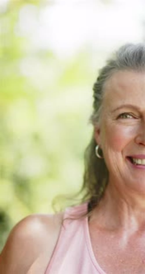 Vertical video: Smiling senior woman outdoors, enjoying sunny day in casual attire