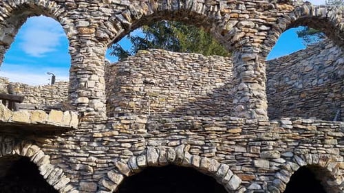 Panoramic view of an abandoned and damaged stone house in nature, tilt right