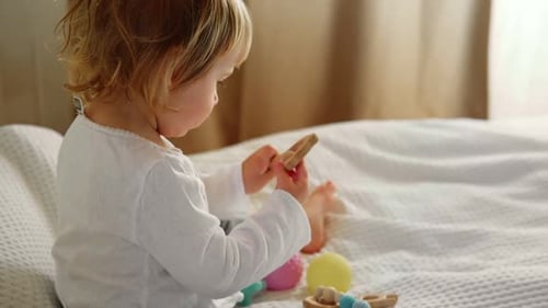 Child Playing with Colorful Toys on Bed