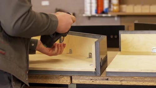 Man Using Screwdriver to Assemble Furniture in Workshop
