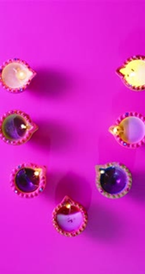 Vidéo verticale de bougies allumées en rang célébrant Diwali sur fond rose, avec espace de copie