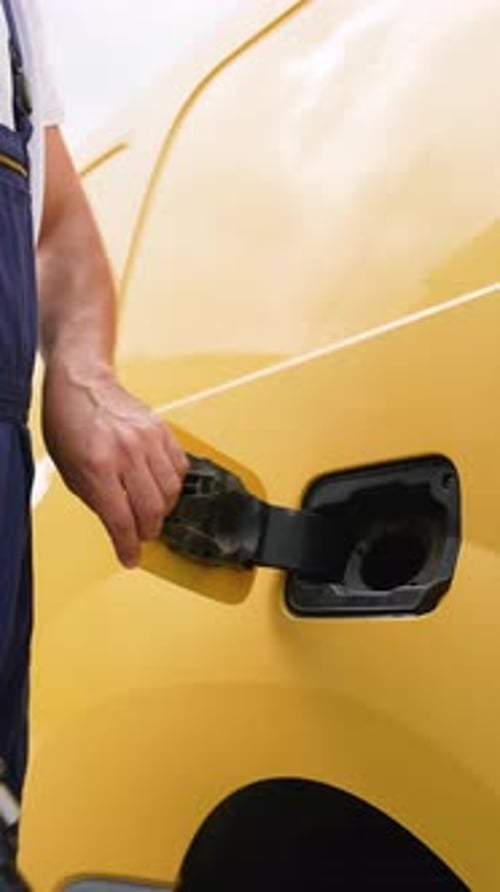 Man Charging Yellow Electric Van with Charging Cable