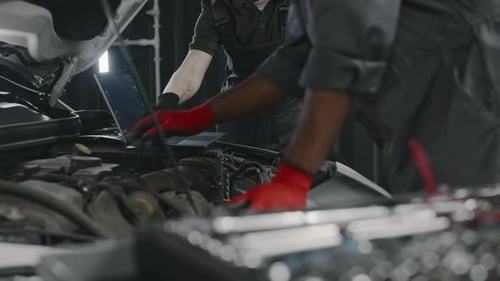 Diverse Car Garage Workers with Laptop Diagnosing Engine Malfunction