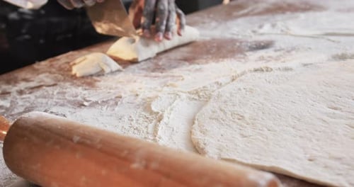 Verschiedene Bäcker arbeiten in der Backküche und schneiden Teig in Zeitlupe auf der Theke