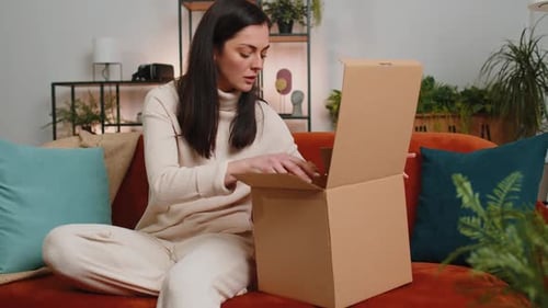 Woman Opens Box on Couch Indoors