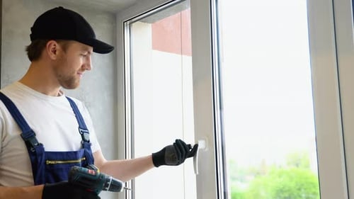 Worker in Overalls Installing a Window Lock for Home Safety The Concept of Protecting a Child From