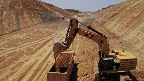 Excavator Filling Truck with Dirt at Construction Site