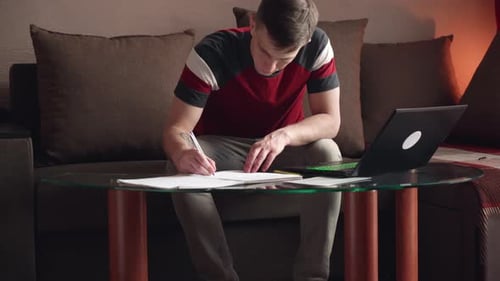 The young man works at home. filling out documents.