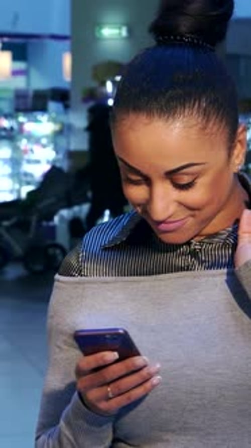 Fröhliche Frau, die beim Einkaufen auf ihrem Handy chattet