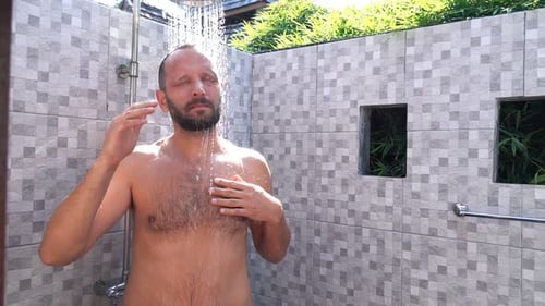 Man Enjoying Refreshing Outdoor Shower on Tropical Vacation