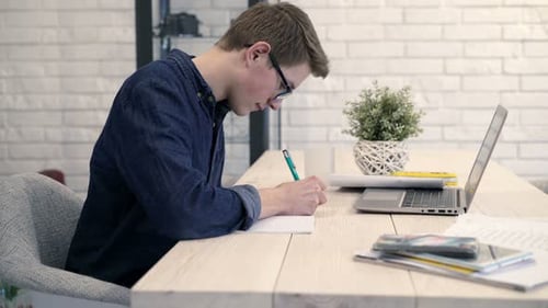 Teenager Studies and Writes at Home Desk